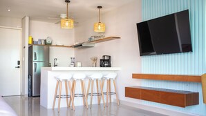 A modern kitchen with a central island, bar stools, a built-in TV, and a refrigerator. - Spectacular Ocean View from 6th floor Beachfront Studio -Aria Ocean Flamingos NV (Nuevo Vallarta)