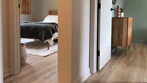 A bedroom with a bed, a bedside table, and a mirror. - Serene Mid-Mod Ranch on 2 Acres in Gardiner (Gardiner)