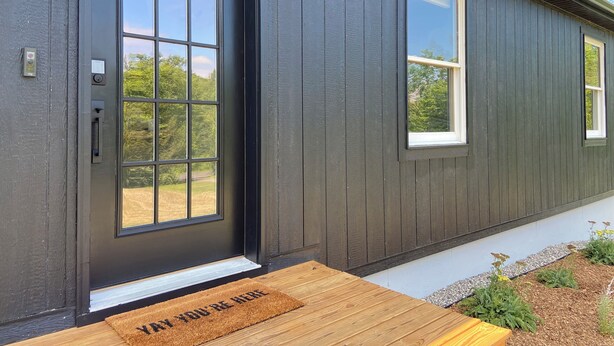A modern house with a dark exterior, large windows, and a wooden front porch. - Serene Mid-Mod Ranch on 2 Acres in Gardiner (Gardiner)