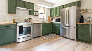 A modern kitchen with green cabinets, stainless steel appliances, and a wooden countertop. - Serene Mid-Mod Ranch on 2 Acres in Gardiner (Gardiner)