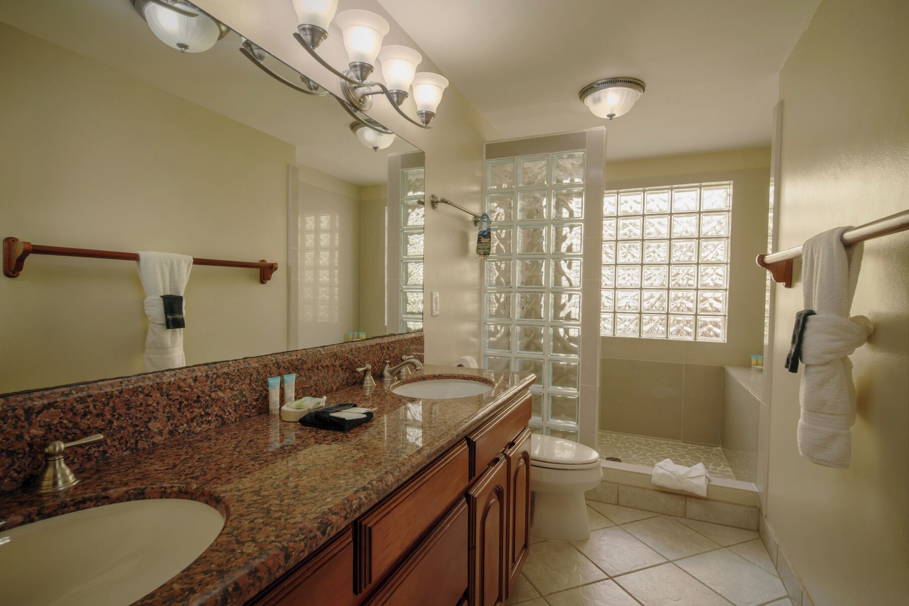 A bathroom with two sinks, a toilet, a shower, and a large mirror.