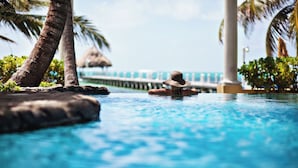 Una persona en una piscina, con palmeras y un puente al fondo.