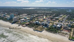 An aerial view of a coastal residential area with beach access, featuring a mix of single-family homes and a prominent blue building. - Flip Flop Living 1 3bdrm, 2.5 bath, STEPS TO SAND! (New Smyrna Beach)