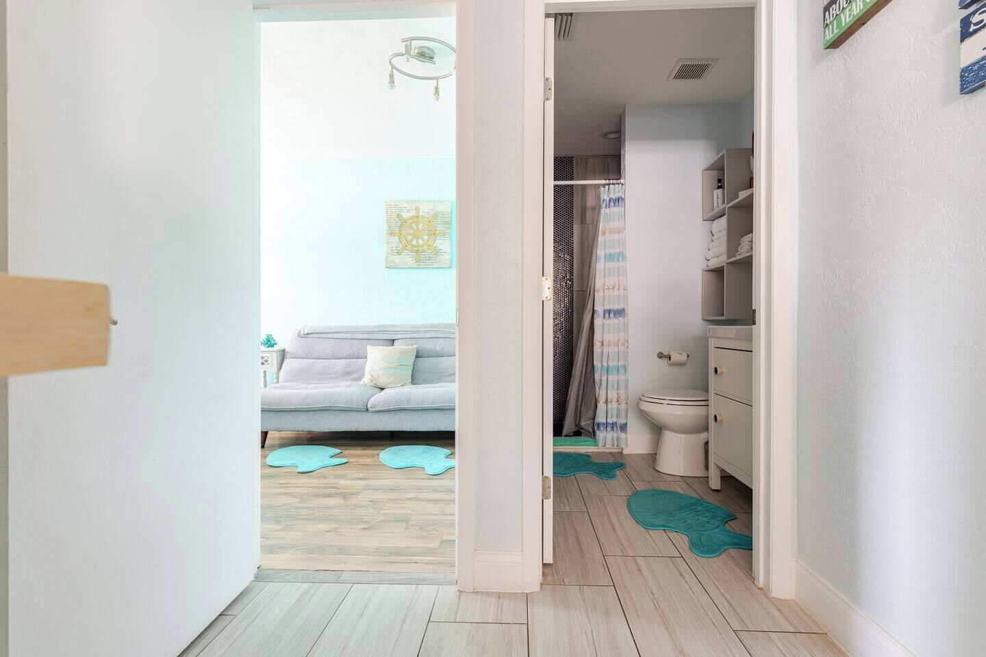 A hallway leading to a bathroom with a toilet, a shower curtain, and a towel rack.