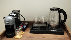 Une machine à café, deux verres, une cafetière et un plateau avec un moulin à caf é et une cuillère.