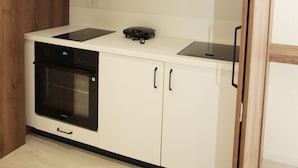 Une cuisine compacte équipée d’un four encastré, d’une plaque de cuisson et d’un four à micro-ondes.
