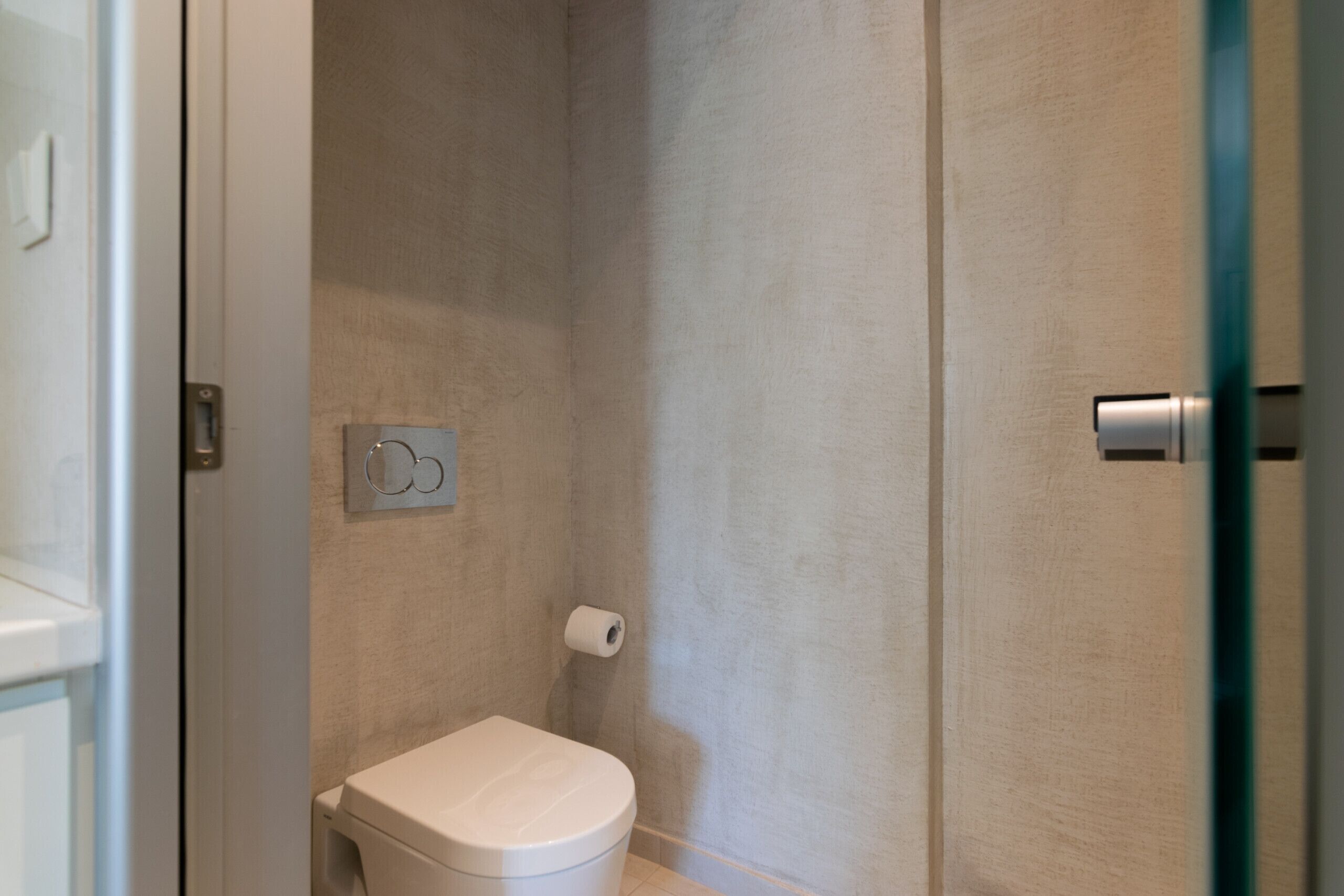 Ein Badezimmer mit Toilette, Handtuchhalter und Duschbereich.