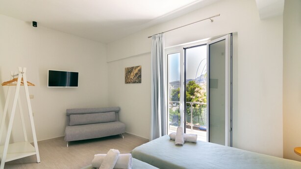 A modern hotel room with a bed, a sofa, a TV, and a balcony with a view. - Secret Nest 13 , studio,near the beach,Plakias (Plakias)