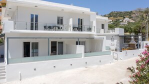 Un edifici modern de dues plantes amb balcons, grans finestres i un terrat pla.
