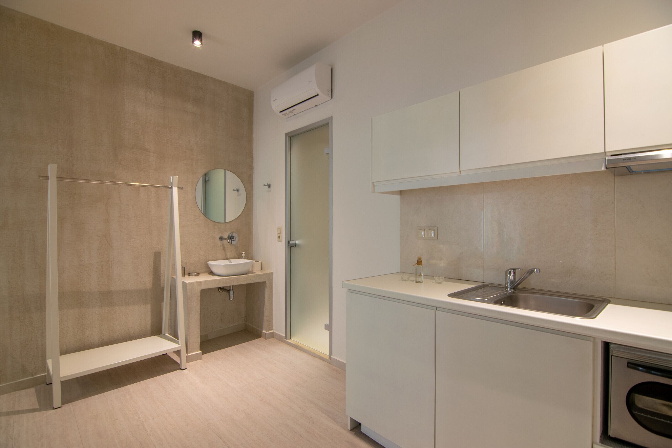 Une cuisine moderne dotée d’un four encastré, d’un évier et d’une cabine de douche en verre.