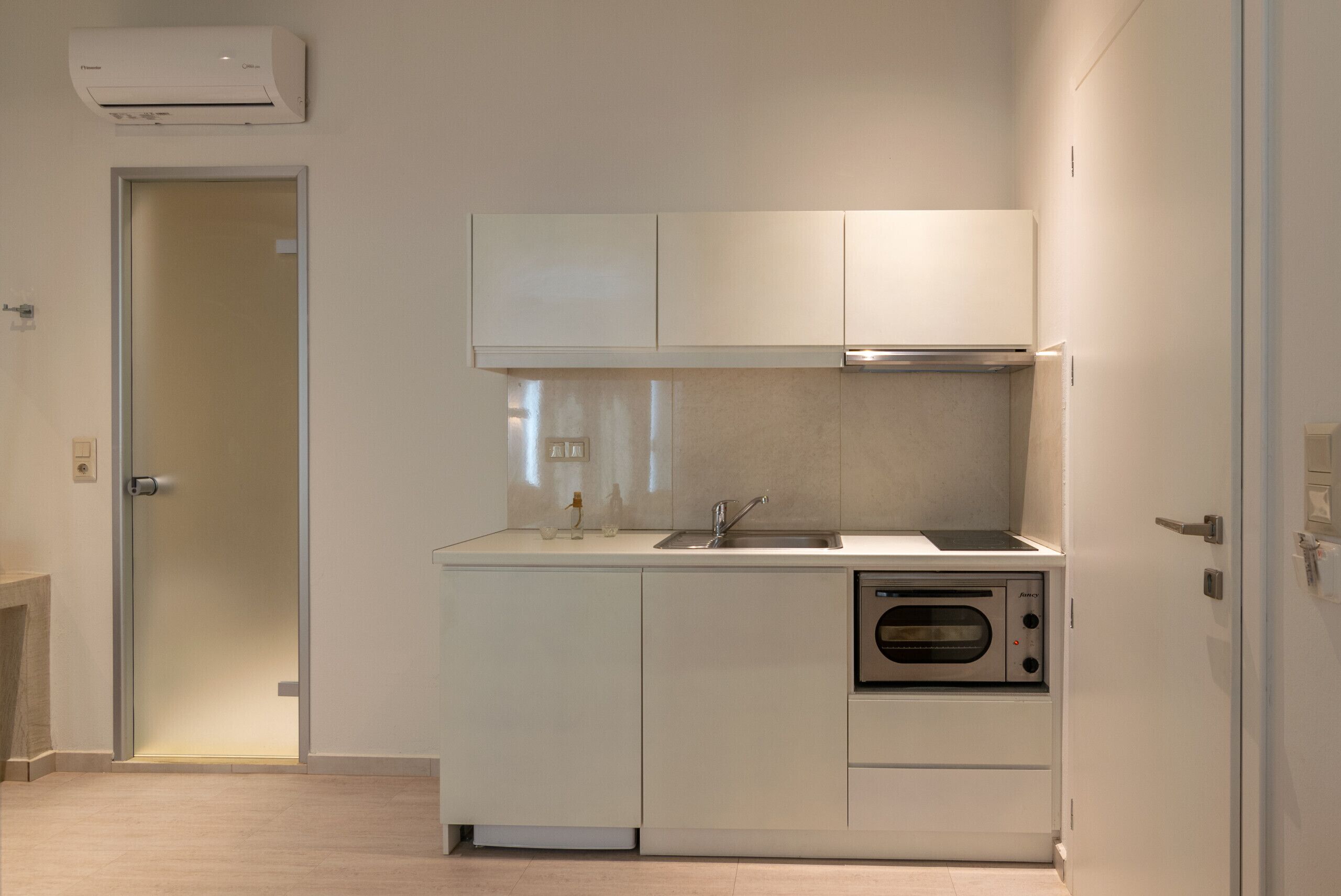 Une cuisine moderne avec des meubles blancs, un évier en acier inoxydable et un four.