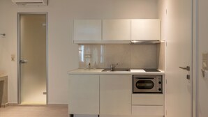 Una cuina moderna amb armaris blancs, un rentaplat i un forn.