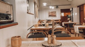 Un interior de restaurante con mesas y sillas de madera, y una radio antigua en la pared.