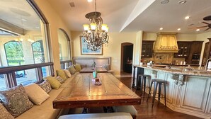 Un comedor amplio con una larga mesa de madera, bancos y una araña.
