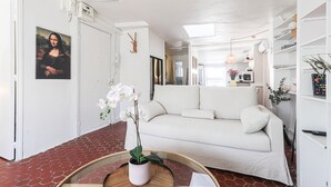 A modern living room with a white sofa, a round coffee table with a vase of flowers, and a painting of the Mona Lisa on the wall.