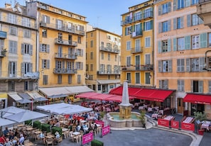 A courtyard with outdoor seating, a fountain, and buildings with balconies.