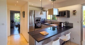 A modern kitchen with a central island, stainless steel appliances, and a pendant light.