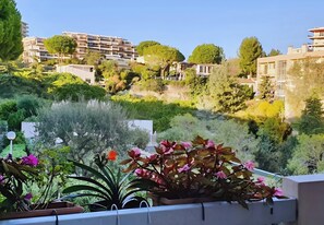 A residential area with multi-story buildings, lush greenery, and potted plants on balconies.