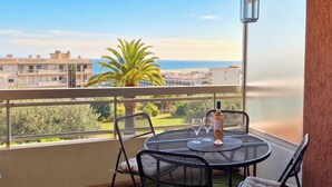 Ein Balkon mit Tisch, Stühlen und einer Weinflasche.