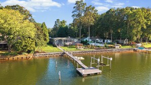 Une propriété au bord du lac, dotée d’un quai, d’un patio couvert et d’une maison avec une terrasse.