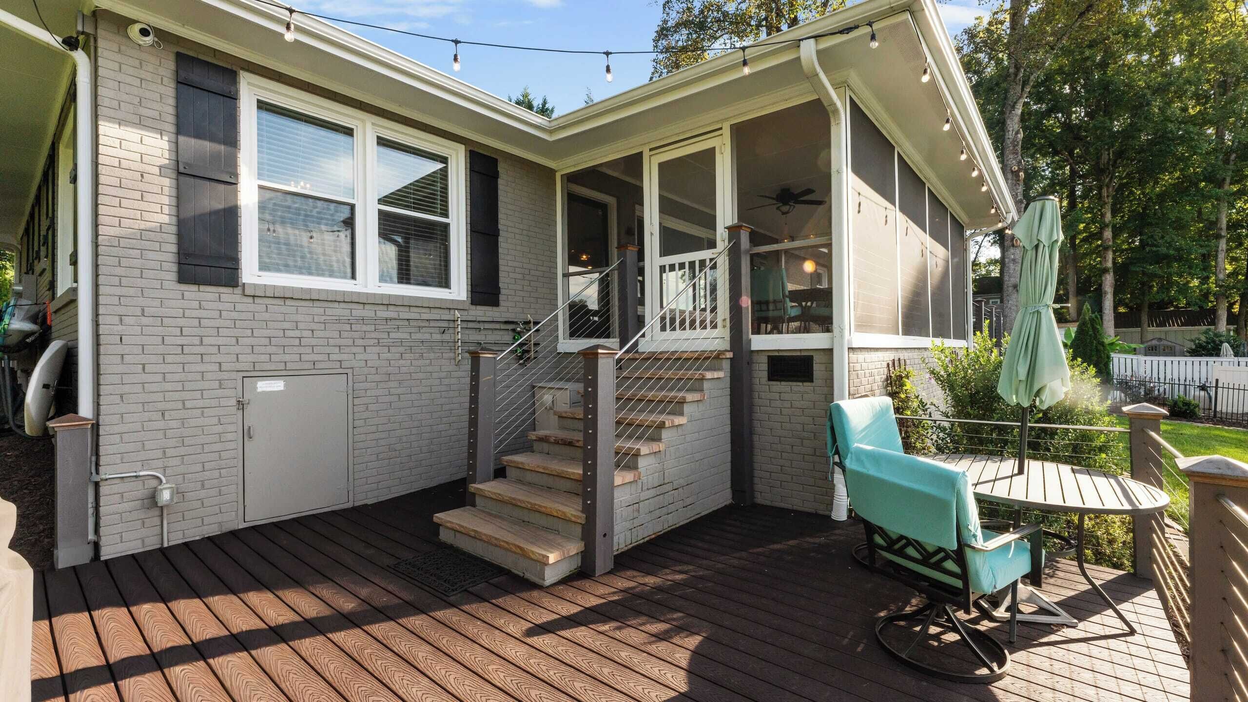 Una casa con terraza techada, una escalera y mobiliario exterior.