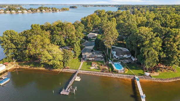 Une propriété située au bord d’un lac, dotée d’un quai, d’une piscine et d’une grande maison entourée d’arbres.