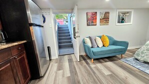 Eine moderne Küche mit Kühlschrank, Holzschränken und einem Essbereich mit blauem Sofa und Teppich.