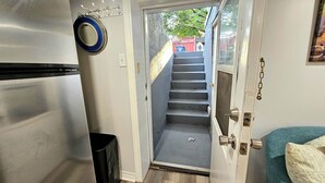 Ein schmaler Flur, der zu einer Treppe mit einer Tür am Ende führt.