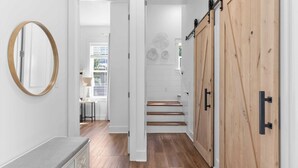 A hallway with a wooden floor, a round mirror, and a wooden sliding door.