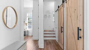 A hallway with a wooden floor, a round mirror, a sliding barn-style door, and a staircase leading to another room.