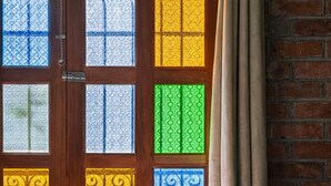 Una habitación con una cama, un ventanal con vidrieras de colores y una pared de ladrillo.