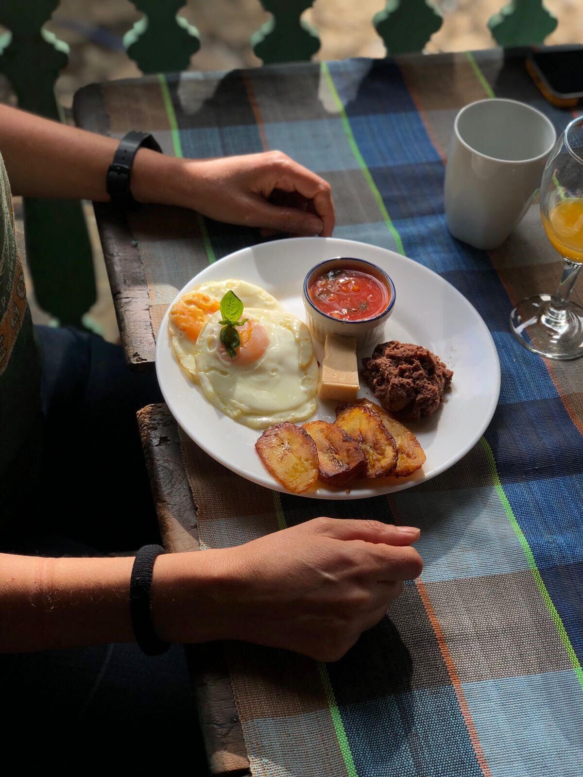 En tallerken med æg, kød tilbehør og en skål salsa, serveret på en ternet dug.