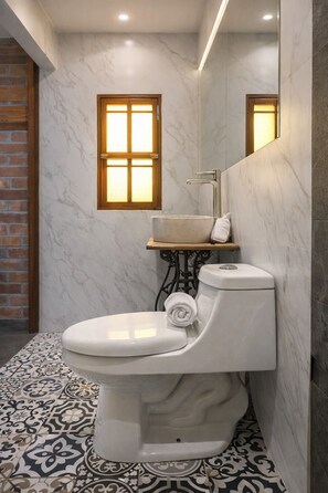 A bathroom with a toilet, a sink, and a window.