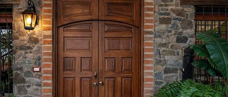 A double wooden door with a stone wall and herringbone pattern above it.