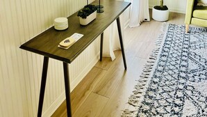 A room with a wooden table, a mirror, a potted plant, and a patterned rug. - 2 bedroom Modern Retreat (Baton Rouge)