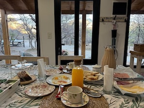 Et morgenbord med tallerkener med mad, en kaffekop og en appelsinjuiceflaske.