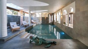 Una piscina interior moderna con sillones de descanso y una estatua.