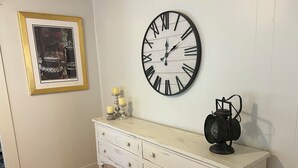 A white dresser with three drawers, a black clock with Roman numerals, and a framed picture on the wall. - Quiet, Peaceful River property on 1.5 acres in Sterlington. (Sterlington)
