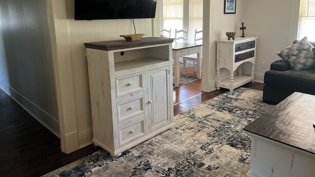 A living room with a TV, white cabinets, a dark sofa, and a patterned rug. - Quiet, Peaceful River property on 1.5 acres in Sterlington. (Sterlington)