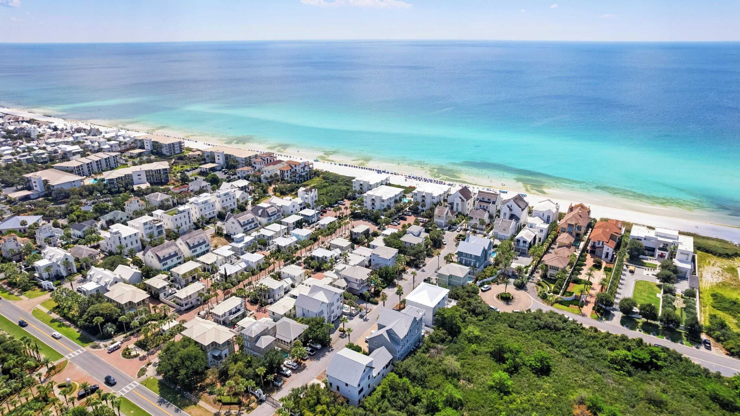 Vista aérea de una zona residencial costera con casas, una playa y una vista despejada del océano.