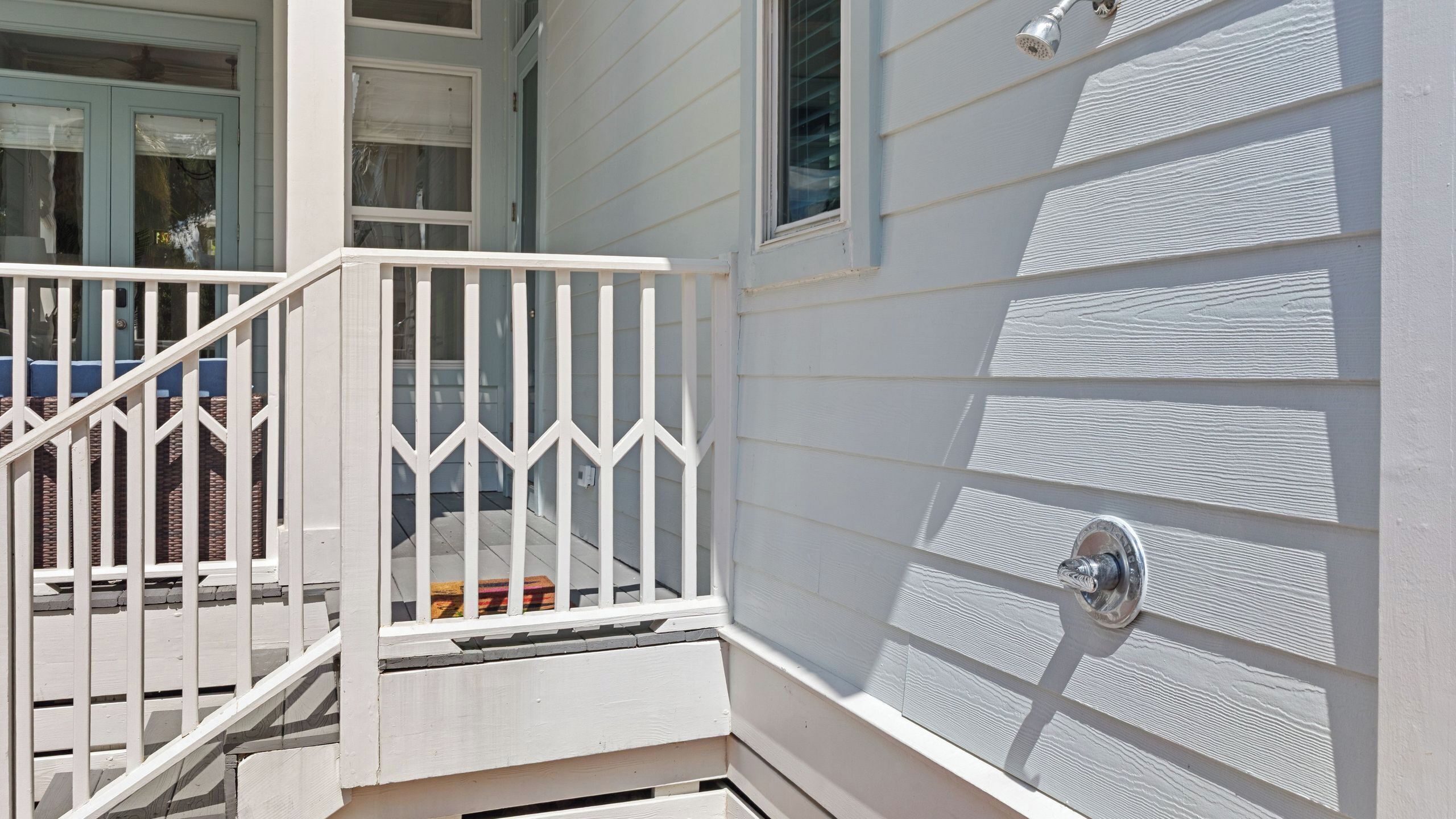 A white exterior with a white railing, a window, and a door with a metal handle.