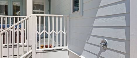 A white exterior with a white railing, a window, and a door with a metal handle.