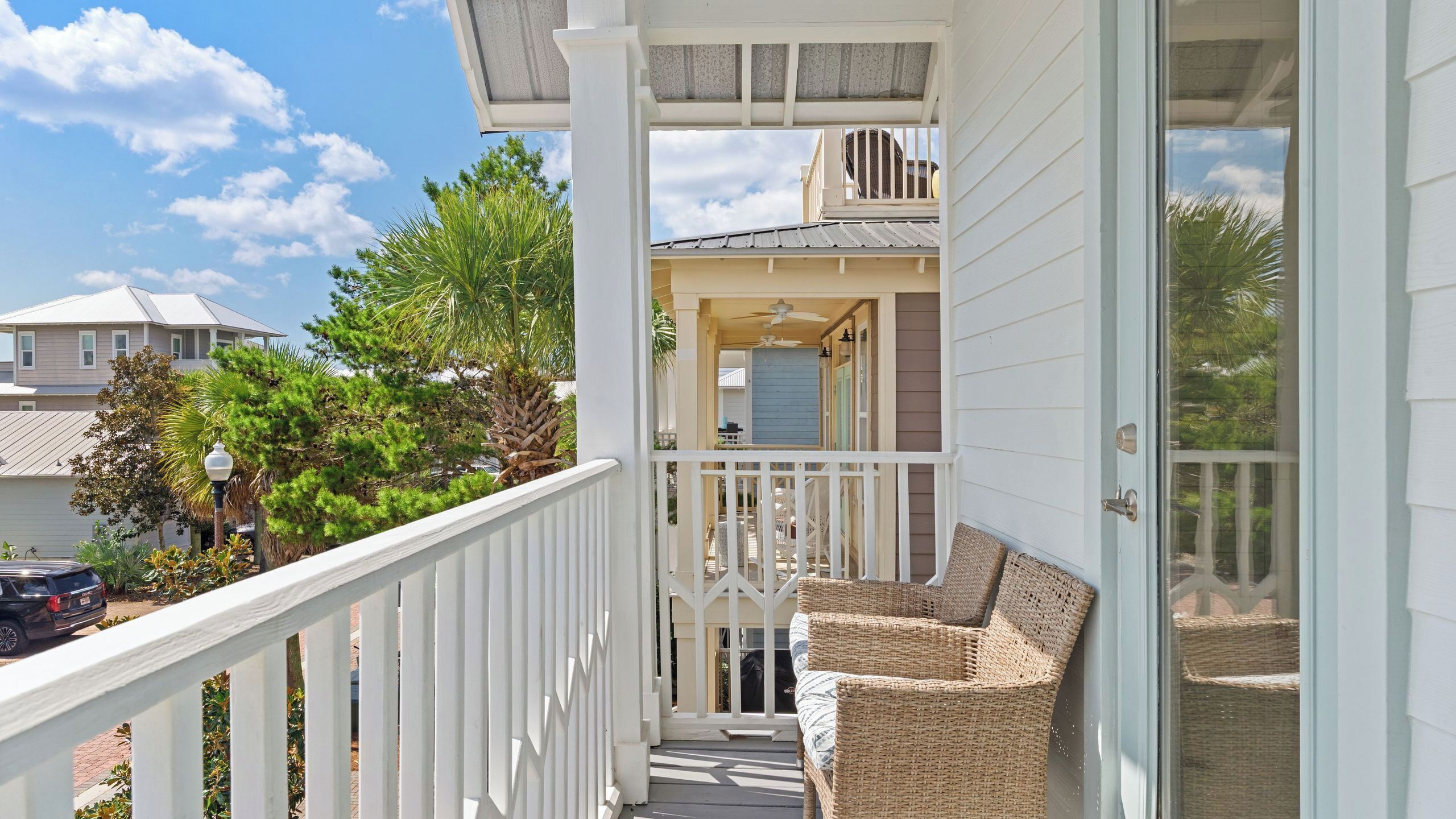 A balcony with wicker furniture, a ceiling fan, and a view of neighboring houses.