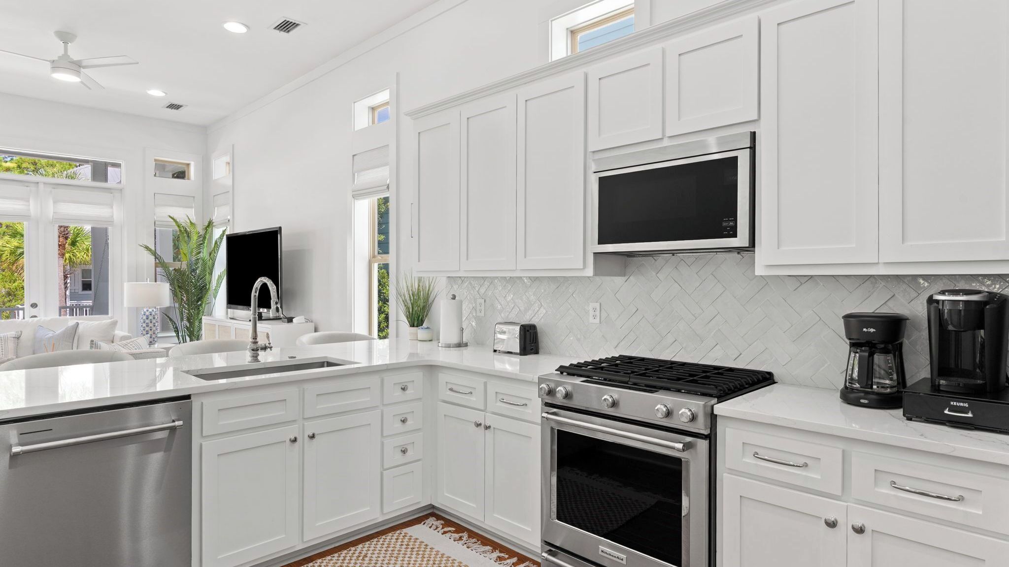 A modern kitchen with white cabinetry, a stainless steel range, a built-in oven, a microwave, and a coffee maker.