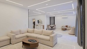 Un salon moderne avec un canapé d’angle, une table basse et un coin repas à l’arrière-plan.