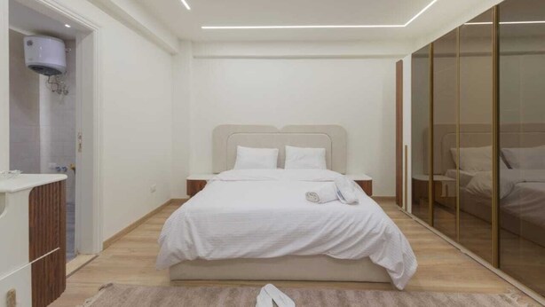 Une chambre moderne dotée d’un grand lit, d’un dressing et d’une salle de bain avec douche.