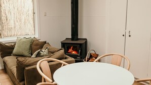 A cozy living room with a sofa, a table, and a wood-burning stove. - Salt Cottage - charming two–bedroom retreat (Port Fairy)