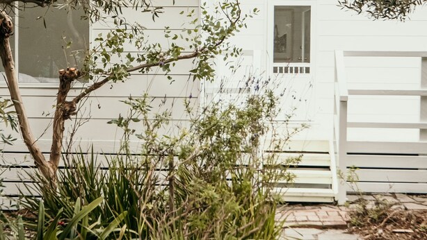 A white house with a wooden deck and a window. - Salt Cottage - charming two–bedroom retreat (Port Fairy)