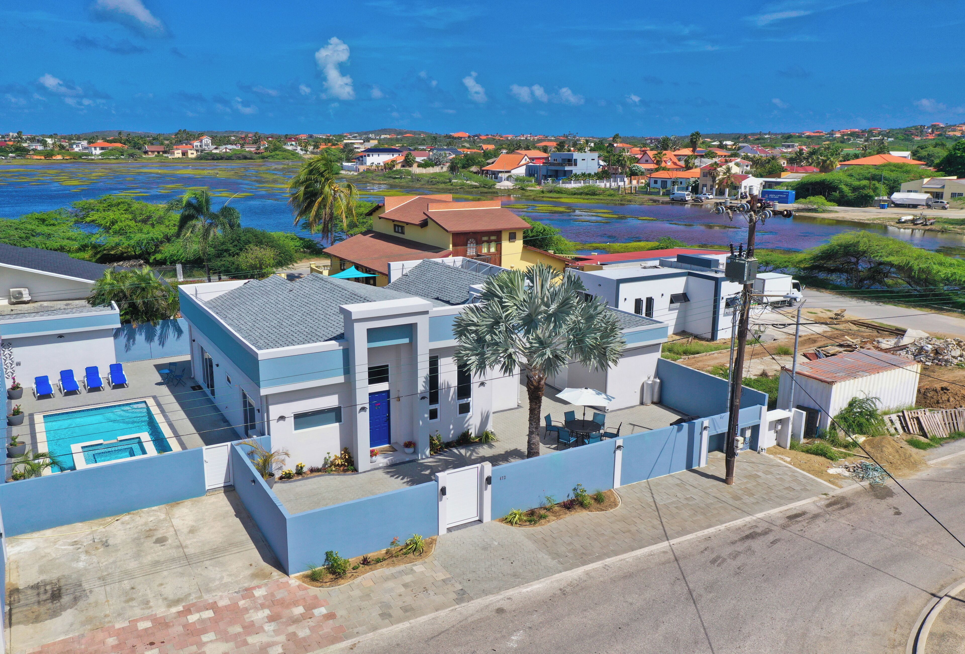 Zona residencial con piscina, una casa azul y vista al agua.