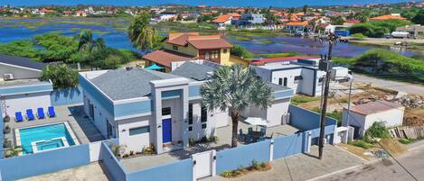 Zona residencial con piscina, una casa azul y vista al agua.